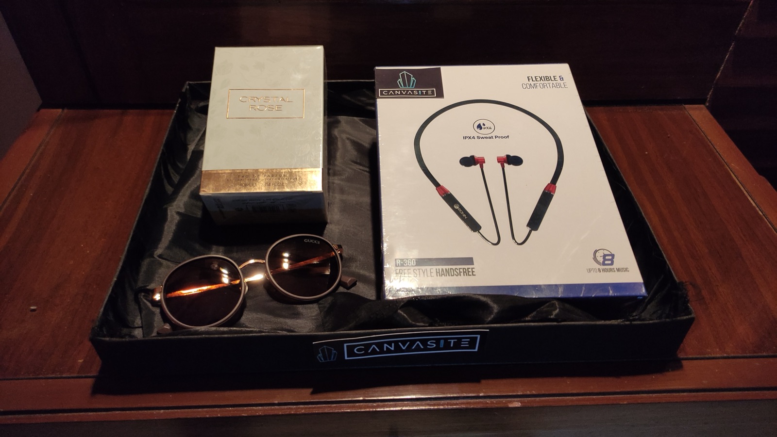 Perfume, earbuds and sunglasses in a black gift box
